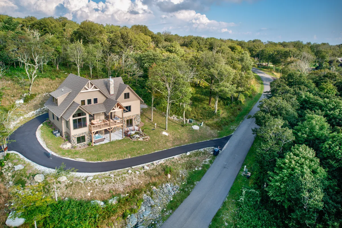 This exterior shot highlights Grandview Pointe’s welcoming facade surrounded by lush trees and a curving driveway, evoking a sense of arrival and seclusion in the mountains. The inviting porch and spacious yard are visible, suggesting ample space for families to gather before or after their adventures.