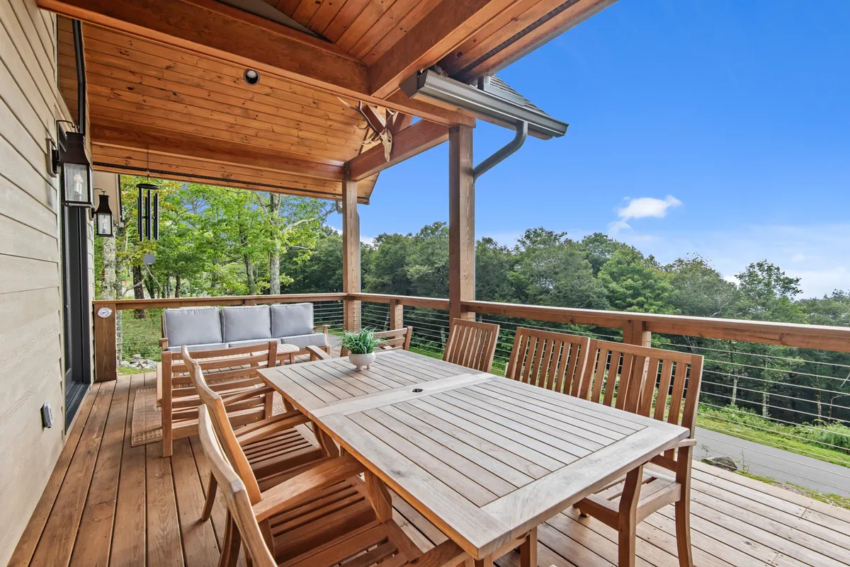 A comfortable outdoor dining area with a wooden table and seating, surrounded by lush greenery. The setting exudes an atmosphere of serenity, perfect for alfresco meals, morning coffee, or evening drinks with friends or partners.