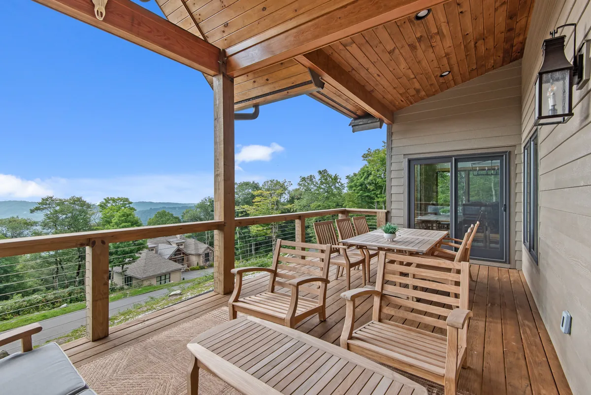 A spacious wooden deck equipped with a dining table and chairs, overlooking a breathtaking mountain view. The setting is ideal for outdoor dining, relaxing, and entertaining guests, with expansive views that capture the natural beauty of the area.